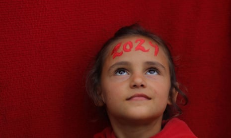 یک دختر فلسطینی در مدرسه UNRWA در دیرالبلاح با چهره‌اش با نقاشی «2024» توسط هنرمند فلسطینی منا الله حمودا.
