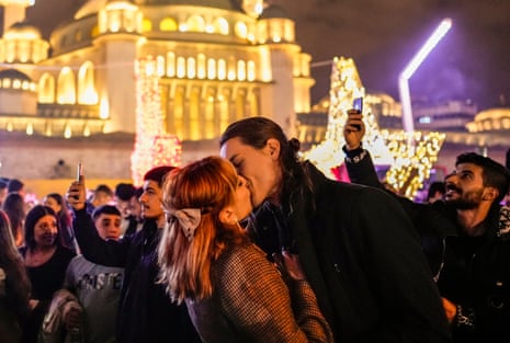 زن و شوهری در حالی که در میدان تقسیم مرکزی استانبول جشن می گیرند، بوسه می زنند.