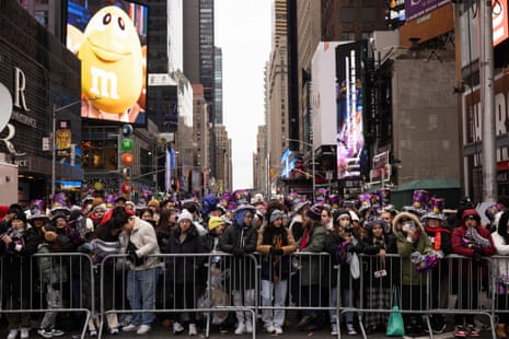 مردم قبل از جشن سال نو در میدان تایمز نیویورک، پشت سنگری منتظر می مانند.